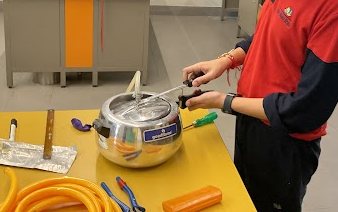 A pressure cooker and tubing set up on a lab bench for the first trial