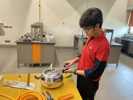 A student preparing the pressure cooker reactor in the school lab