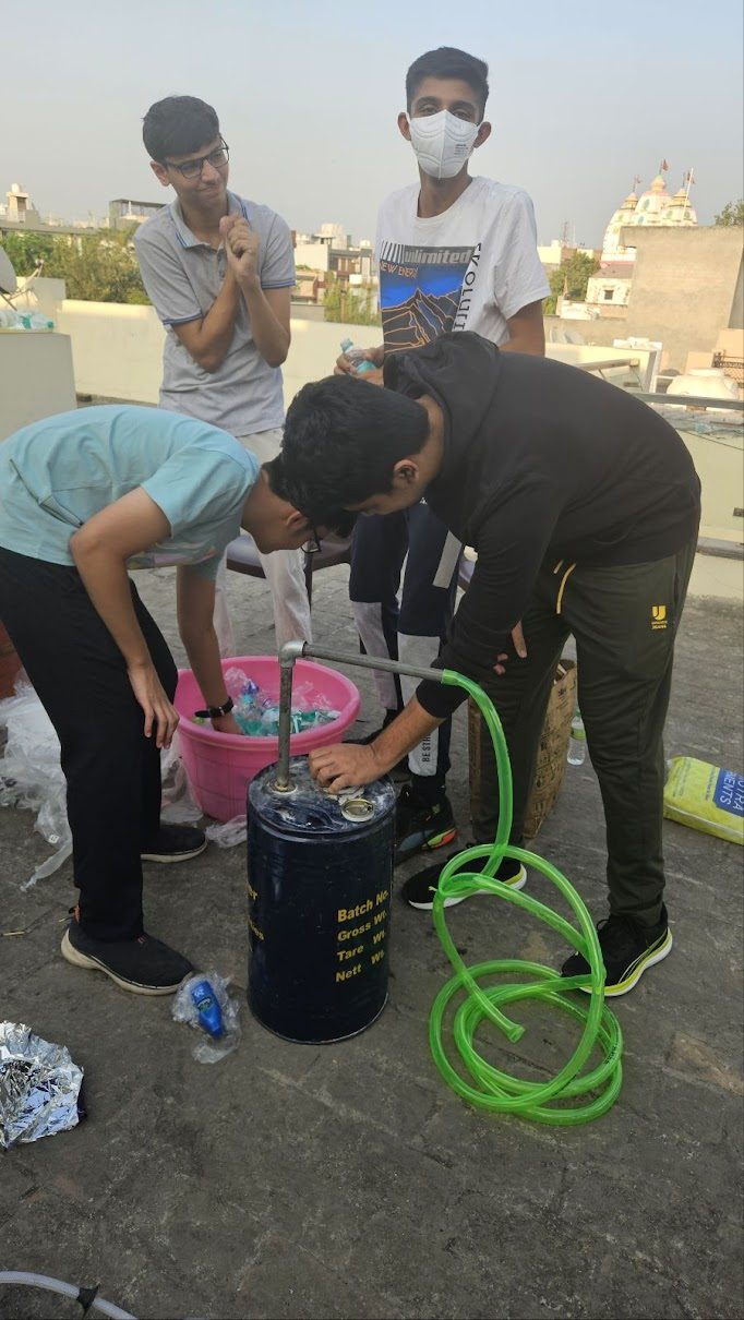 Students loading plastic into the recycled drum reactor